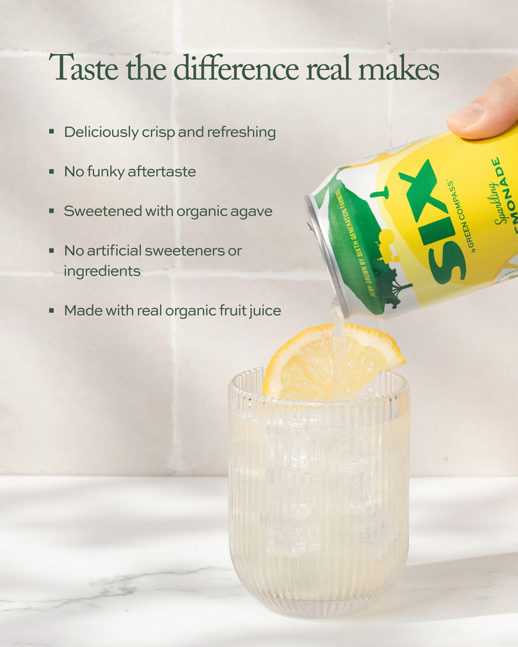 SIXS sparkling lemonade being poured into a glass with a lemon slice, against a white tiled background on a white marble surface